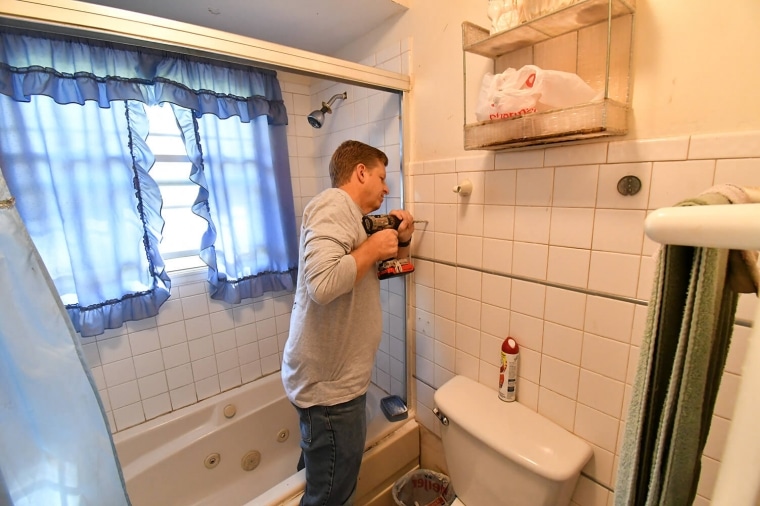 Man using drill to make bathroom safety modification for a senior