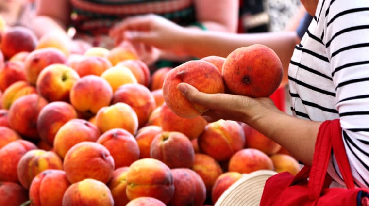 Woman shopping for peaches at the local farmers market