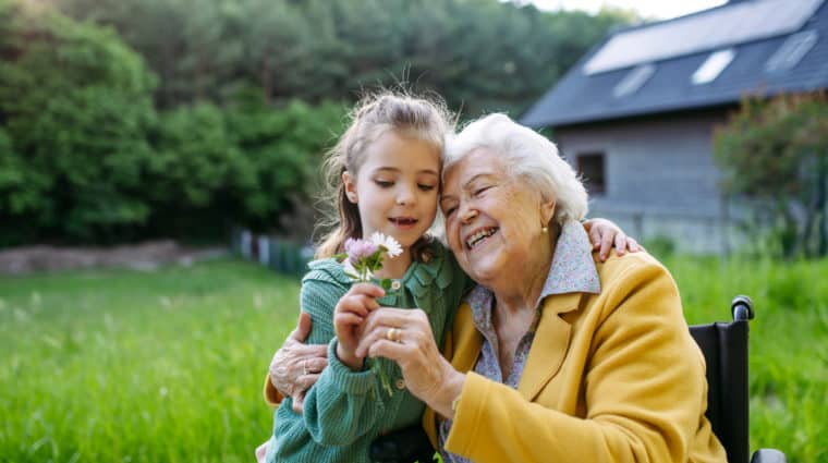 Granddaughter spending time with elderly grandma, picking wildlflowers, Senior lady in wheelchair spending time in nature