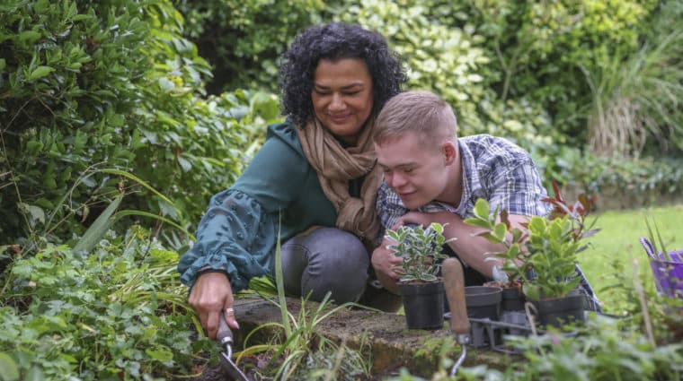Mother and son with disabilities in the garden planting