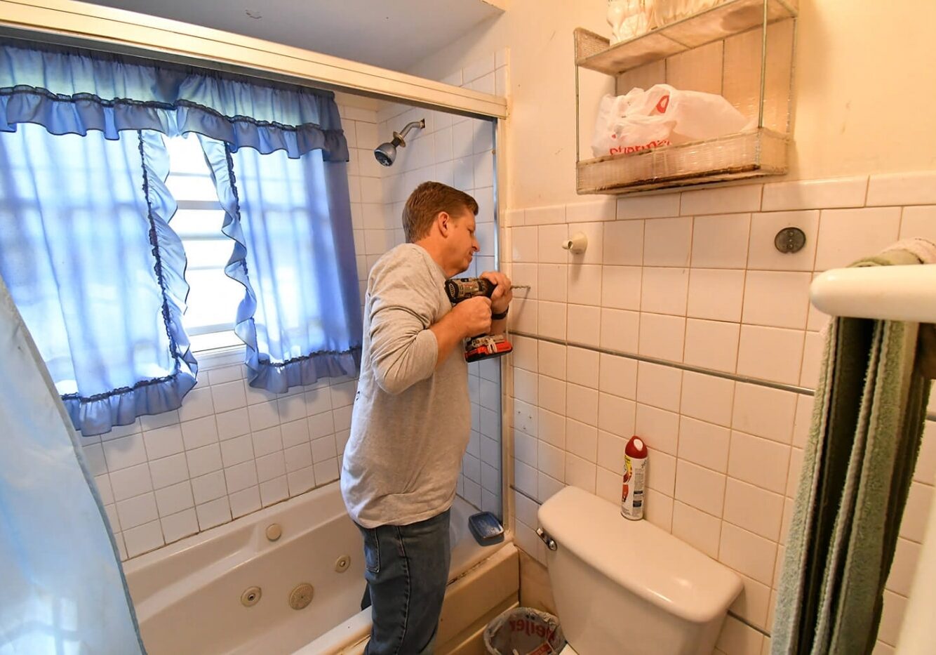 Man using drill to make bathroom safety modification for a senior