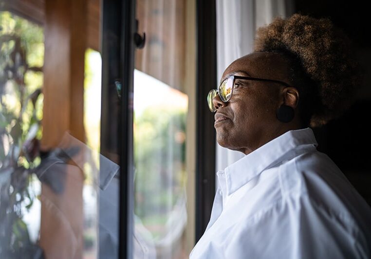 Isolated Senior Looking out Window at Neighborhood