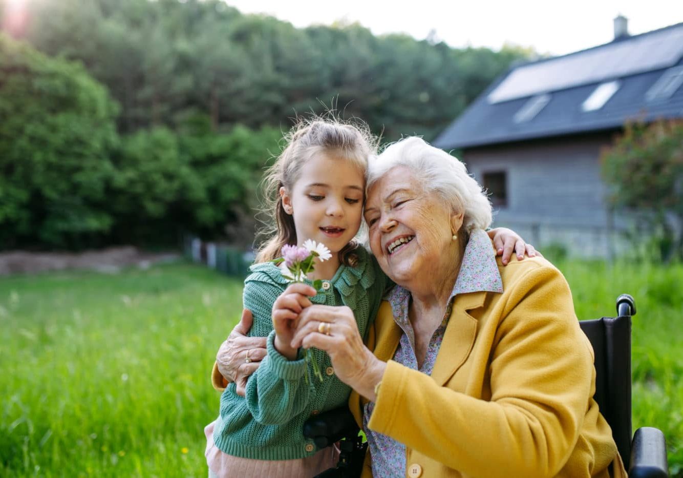 Granddaughter Spending Time With Elderly Grandma, Picking Wildflowers. Senior Lady In Wheelchair Spending Time In Nature. Granddaughter spending time with elderly grandma, picking wildlflowers, Senior lady in wheelchair spending time in nature