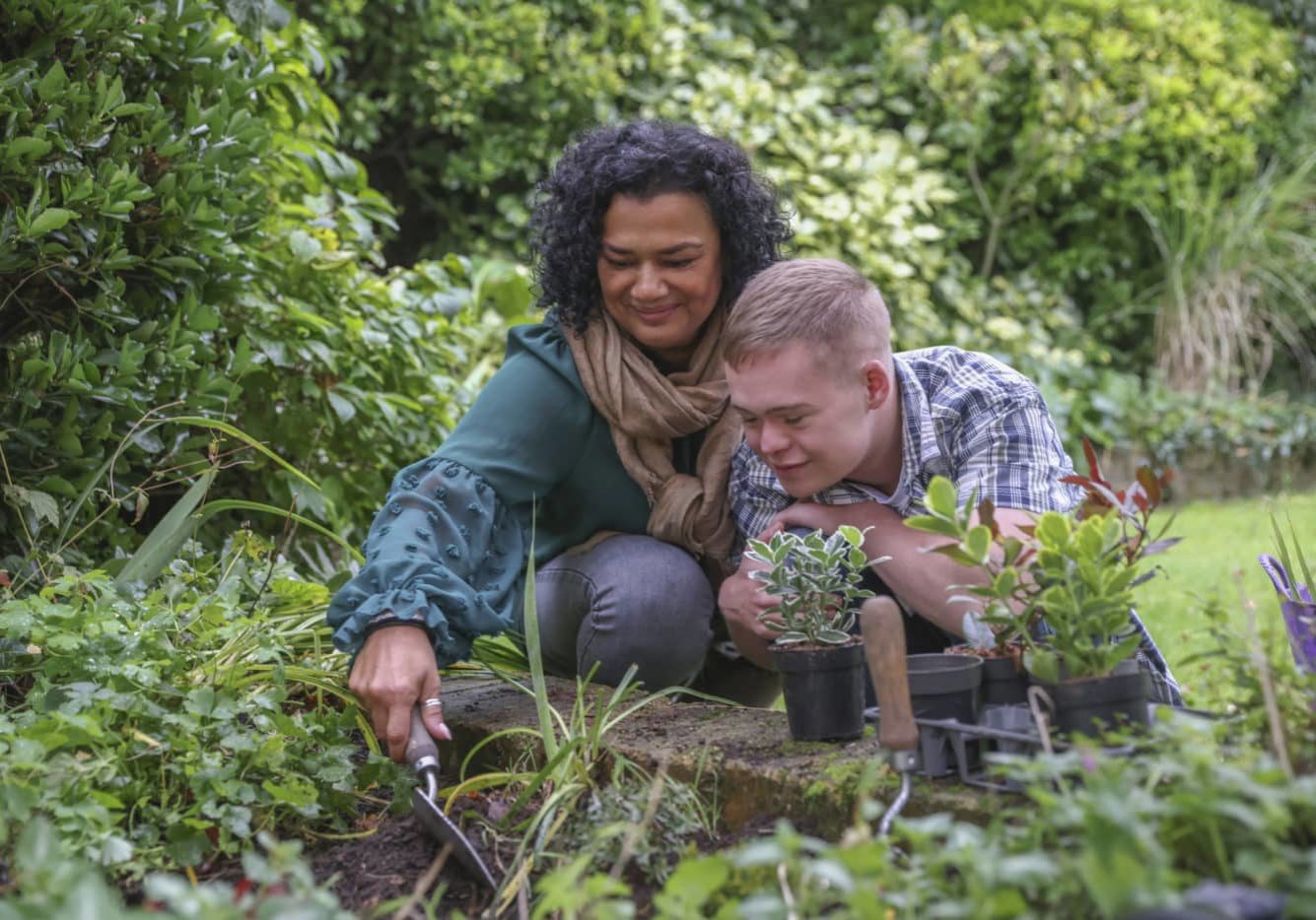 Mother and son with disabilities in the garden planting